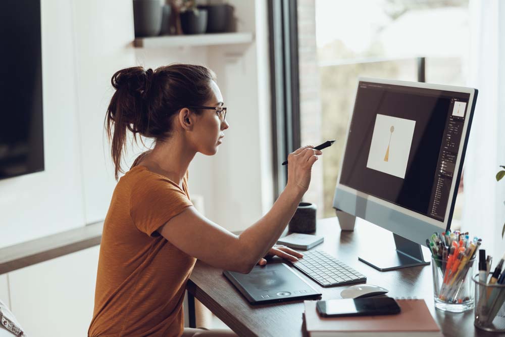 Woman designing a logo with pen pointing at the screen